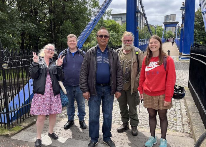 A group of people standing in front of a blue bridge.