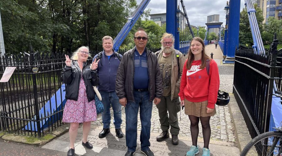 A group of people standing in front of a blue bridge.