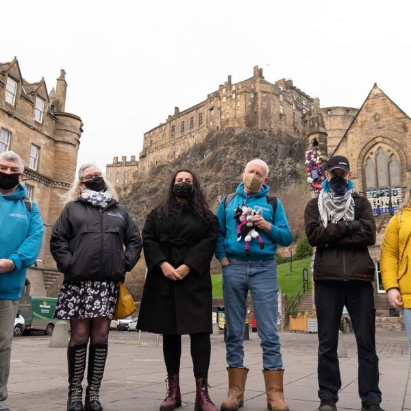A group of people wearing face masks in front of edinburgh castle.