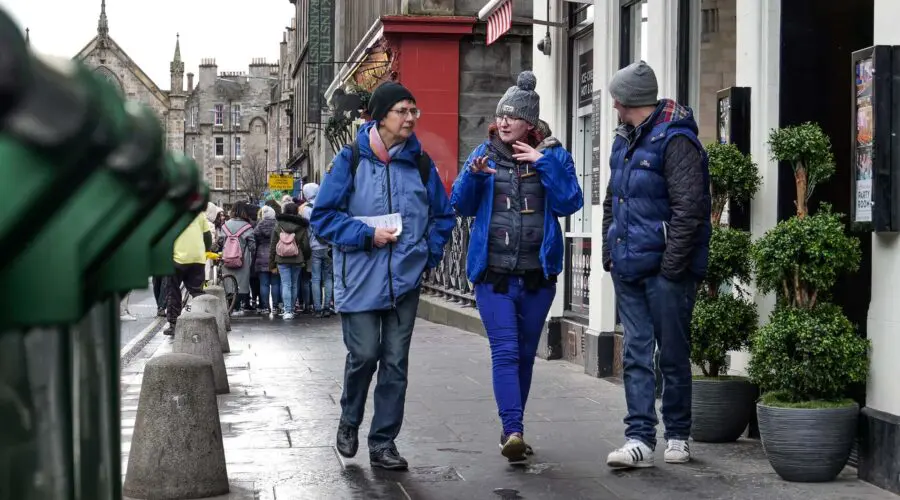 A group of people walking down a street in edinburgh.