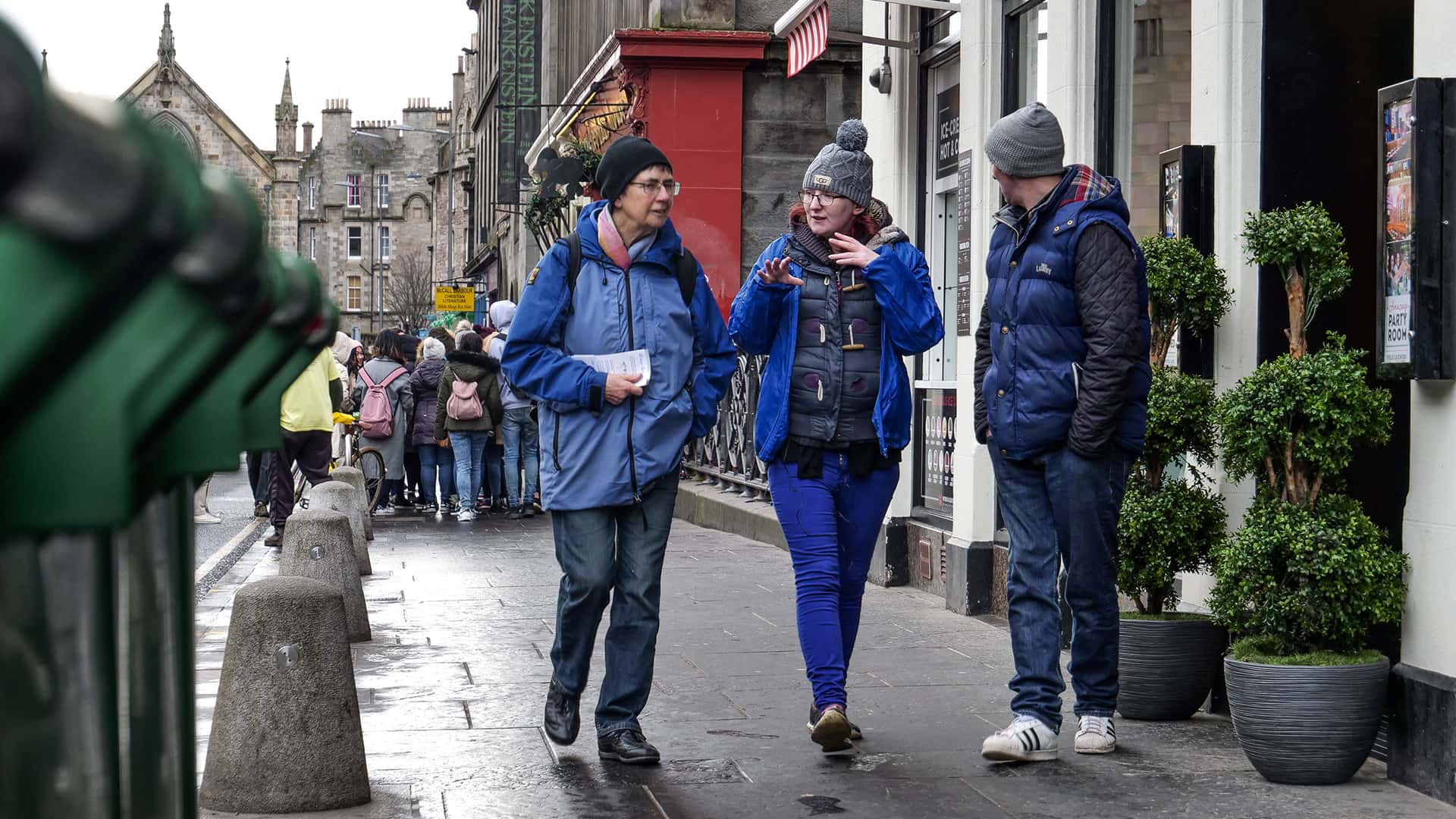 A group of people walking down a street in edinburgh.