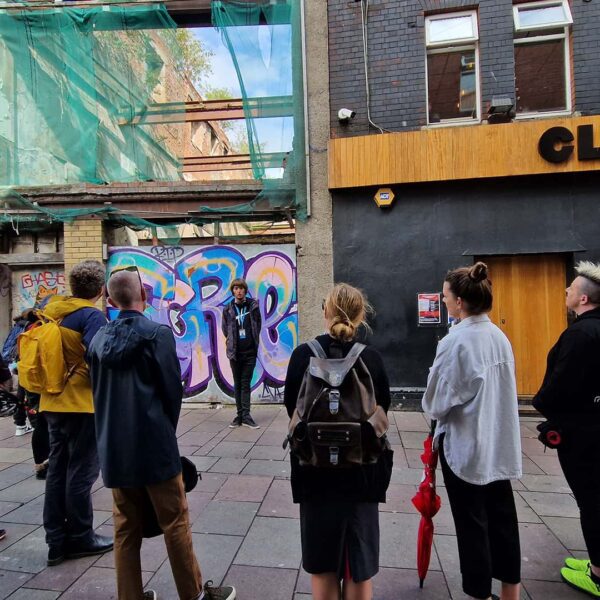 A group of people standing in front of a building with graffiti.