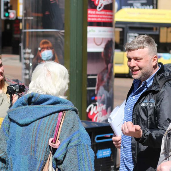 Nic and a group of people enjoying a Wonderwalk on the streets of Manchester, engaging in lively conversations.