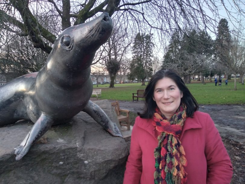 A woman standing next to a statue in Cardiff.